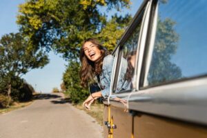 Jeune fille à l'arrière d'une voiture, qui part pour des vacances en famille