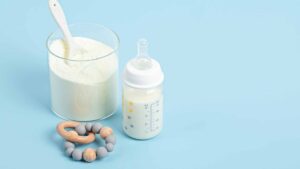 Poudre de lait pour bébé à côté d'un biberon